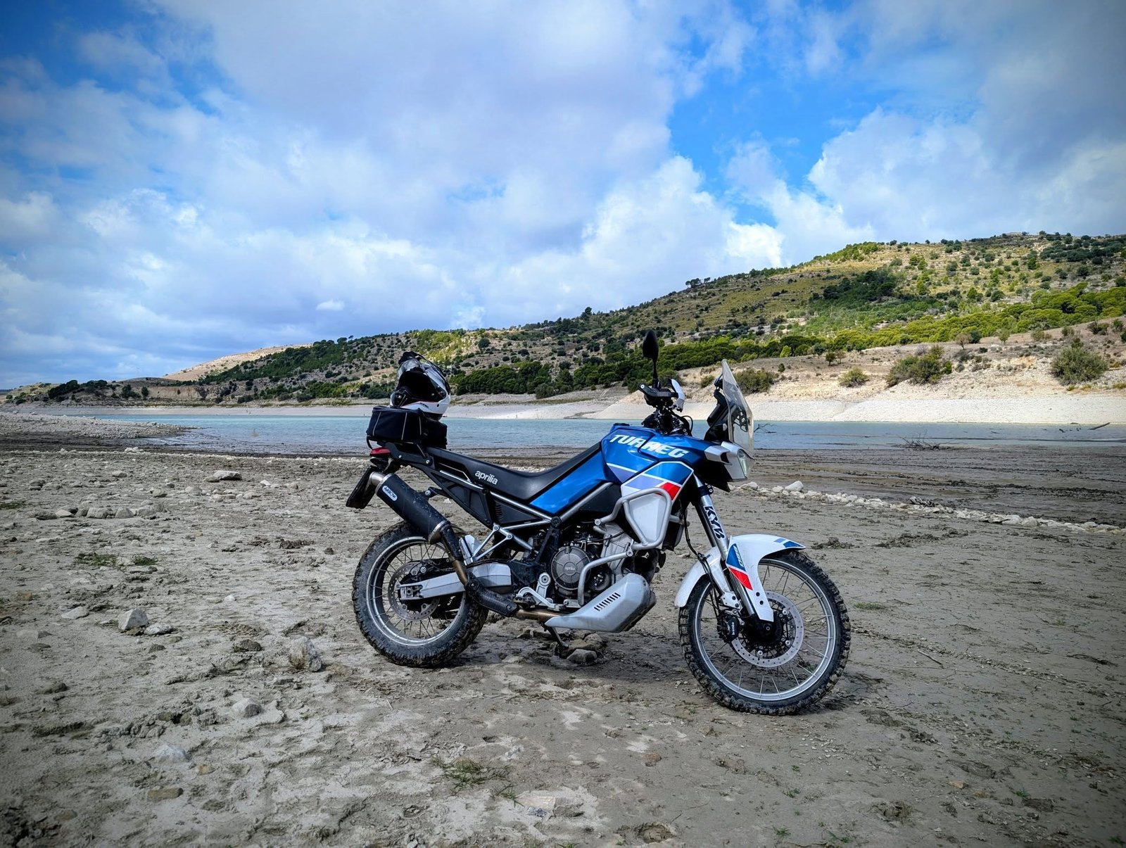 aprilia tuareg 660 parcheggiato vicino a un fiume e una collina verde bassa al di là del fiume