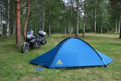 aprilia etv1000 parcheggiata sotto i pini di un bosco in campeggio e vicino a piccola tenda della vaude