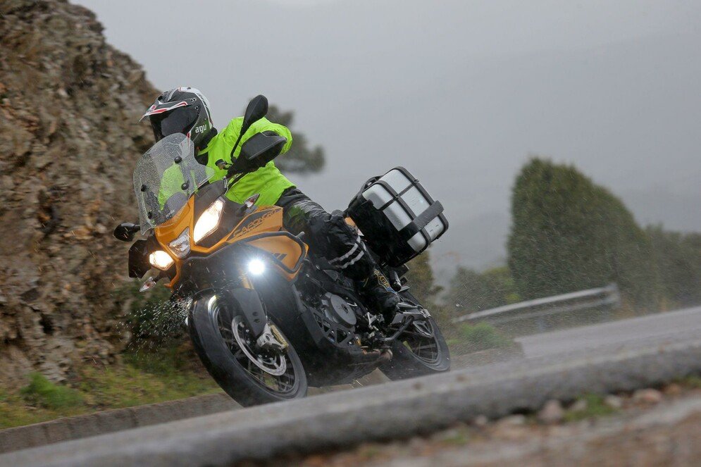 aprilia camponrd 1200 con bagaglio in viaggio sotto la pioggia. il pilota indossa una giacca giallo fluorescente